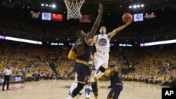 Stephen Curry (30) Golden State Warriors attaque avec le ballon face à LeBron James (23) de Cleveland Cavaliers au cours de la première mi-temps du deuxième match de la finale NBA de basket-ball à Oakland, en Californie., 5 juin 2016. (Ezra Shaw, Getty Images via AP, Pool