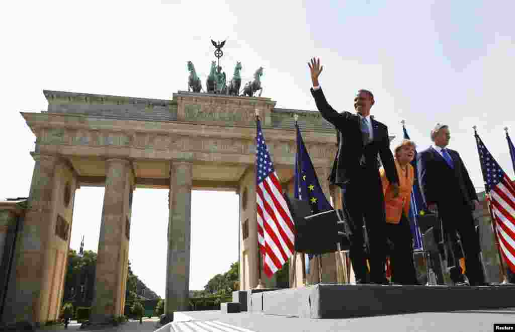 Flanked by Chancellor Angela Merkel and Berlin Mayor Klaus Wowereit, U.S. President Barack Obama waves at the Brandenburg Gate in Berlin June 19, 2013.