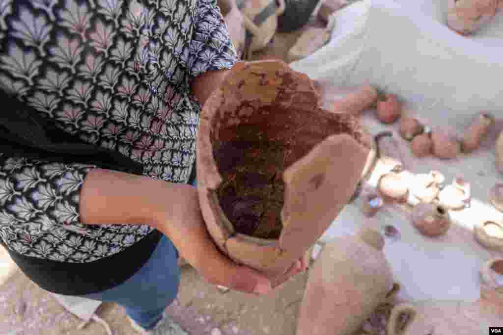 An archeologist shows remnants of wine in a jar discovered at the site in Luxor, Egypt, April 10, 2021. (Hamada Elrasam/VOA)