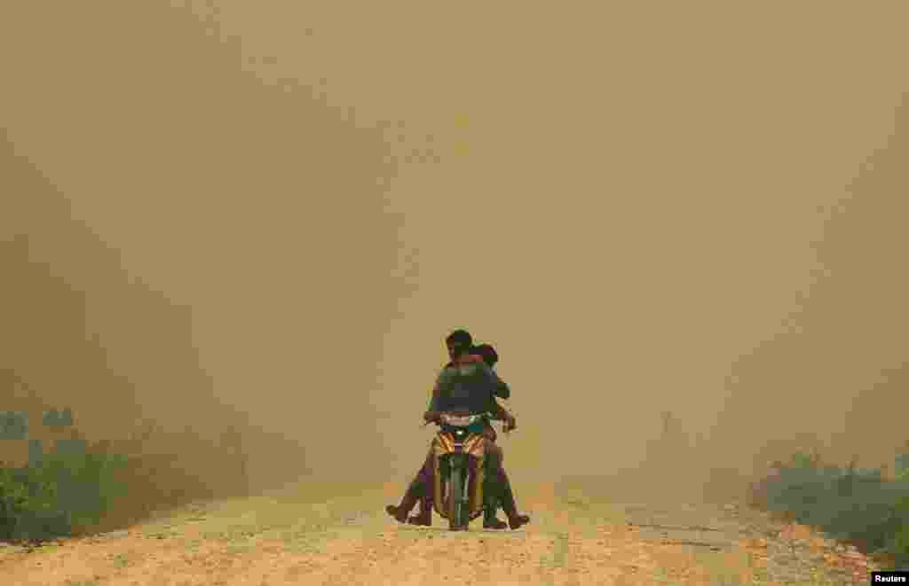 Villagers ride a motorcycle in haze in Dumai, Indonesia, June 21, 2013.
