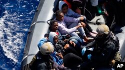 Des migrants secourus au large des côtes libyennes sont assis dans un bateau de la Marine allemande lors de l’opération anti-passeurs, le 29 mars 2016.