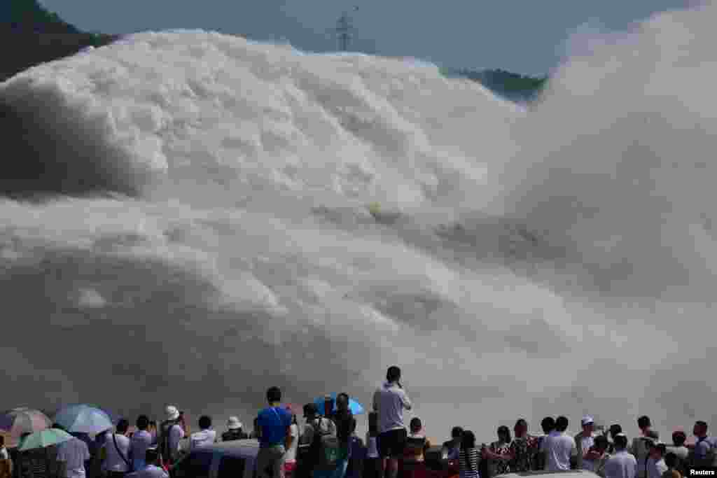 Visitors watch as water gushes from a section of the Xiaolangdi Reservoir on the Yellow River, in Luoyang, Henan Province, China.