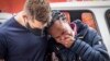 A woman is comforted outside the historical home of Anglican Archbishop Desmond Tutu, in Soweto, Johannesburg, South Africa, Dec. 27, 2021.