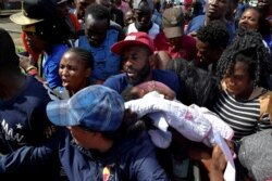 FILE - A migrant from Cameroon holds his baby while trying to enter the Siglo XXI immigrant detention center to request humanitarian visas, issued by the Mexican government, to continue to the U.S., in Tapachula, Mexico, July 5, 2019.