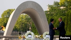 Presiden Barack Obama (kanan) menyalami PM Jepang Shinzo Abe user meletakkan karangan bunga di Tugu Peringatan Perdamaian di Hiroshima, Jepang (27/5).