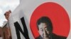 A South Korean man stands next to a sign with a picture of the Japanese Prime Minister Shinzo Abe during a rally to denounce Japan's trade restrictions on South Korea in Seoul, South Korea, Aug. 8, 2019.