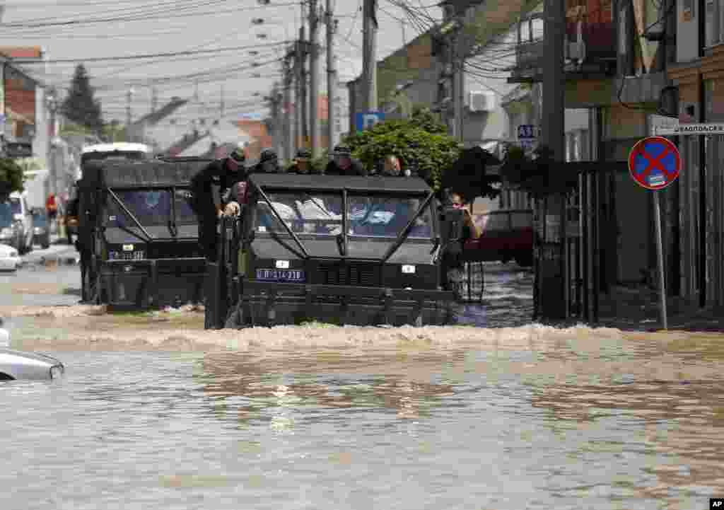 Police vehicles drive through a flooded street in Obrenovac, Serbia, May 20, 2014.