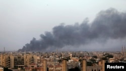 Asap hitam membubung menyusul bentrokan dua kelompok di Benghazi, Libya (23/8).