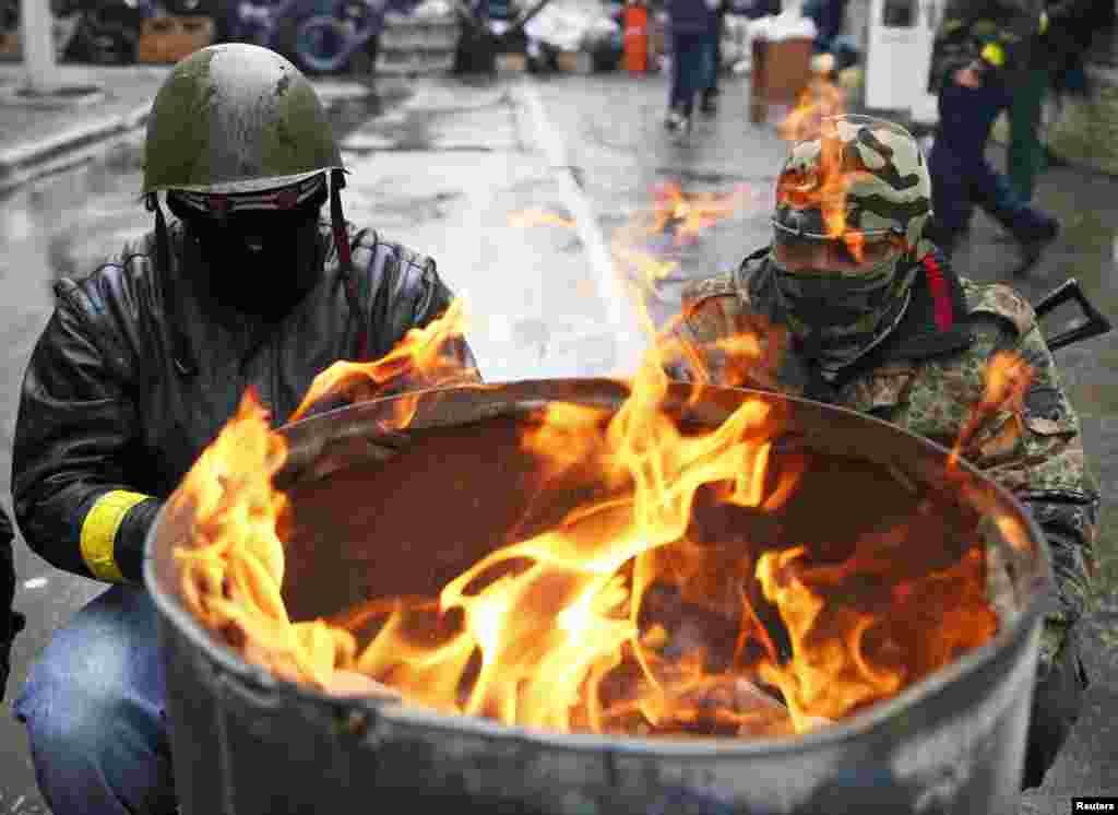 Pro-Russian men gather around a fire at a barricade near the police headquarters in Slovyansk, April 13, 2014. 