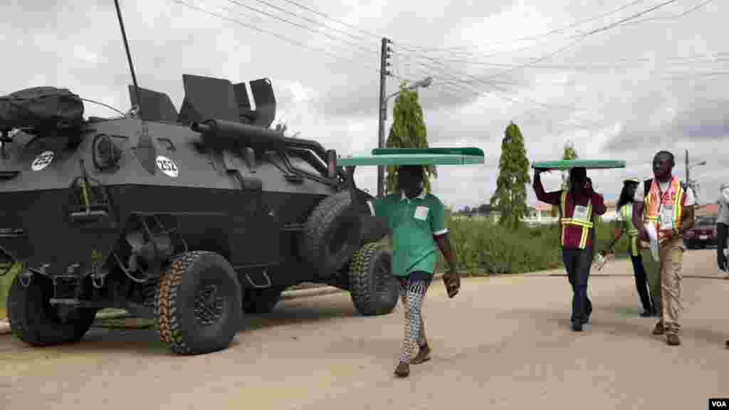 Des agents de la Commission électorale nationale indépendante transportent sur la tête du matériel électoral sous haute sécurité des chars de l’armée aux bureaux de vote d’Otuoke, dans l'État de Bayelsa samedi 28 mars 2015.