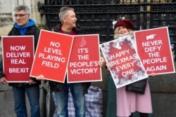 FILE - Pro-Brexit demonstrators hold signs outside the Houses of Parliament, in London, Britain, Dec. 17, 2019.