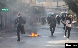 Kurdish protesters run away from tear gaz during a rally against the Kurdistan Regional Government (KRG) in Sulaimaniyah, Iraq, Dec. 18, 2017.