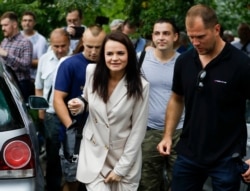 Sviatlana Tsikhanouskaya, candidate for the presidential elections, center, surrounded by her supporters walks after voting at a polling station in Minsk, Belarus, Aug. 9, 2020.