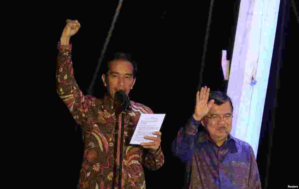 Presiden Indonesia terpilih Joko "Jokowi" Widodo mengangkat tangan saat menyampaikan pidato kemenangan, didampingi Wakil Presiden terpilih Jusuf Kalla, di atas kapal phinisi di Pelabuhan Sunda Kelapa (22/7). (Reuters/Beawiharta)