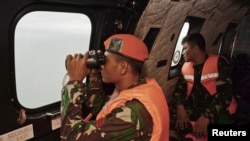Prajurit TNI AU di helikopter Super Puma menggunakan teropong untuk memantau perairan setempat pada operasi pencarian korban jatuhnya pesawat AirAsia penerbangan 8501 di Laut Jawa, Kamis (1/1).