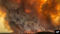 FILE - Wildfires rage under plumes of smoke in Bairnsdale, Australia, Dec. 30, 2019.