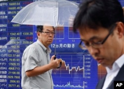 FILE - A man walks past an electronic stock indicator of a securities firm in Tokyo on June 7, 2016.