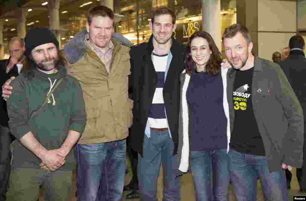 Greenpeace activists Iain Rogers (L), Anthony Perrett (2nd L), Alexandra Harris (2nd R), Phillip Ball (R) and video cameraman Kieron Bryan (C) pose for photographers after arriving at St. Pancras station in central London, England, Dec. 27, 2013.
