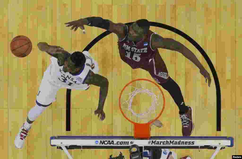 Penyerang dari tim Kansas Jayhawks Jamari Traylor (nomor jersey 31) dan pemain tengah New Mexico State Aggies Tshilidzi Nephawe (nomor jersey 15) berebut bola pada babak pertama putaran kedua Turnamen NCAA 2015 di CenturyLink Center, di Omaha, Nebraska. (Jasen Vinlove-USA TODAY Sports) 