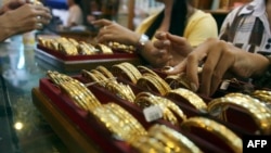 Myanmar vendors arranging a display of gold jewellery at a jewellery shop at Chinatown in downtown Yangon. Housewives huddle over jewellery counters in Yangon's bustling Chinatown -- but they do not have fashion o