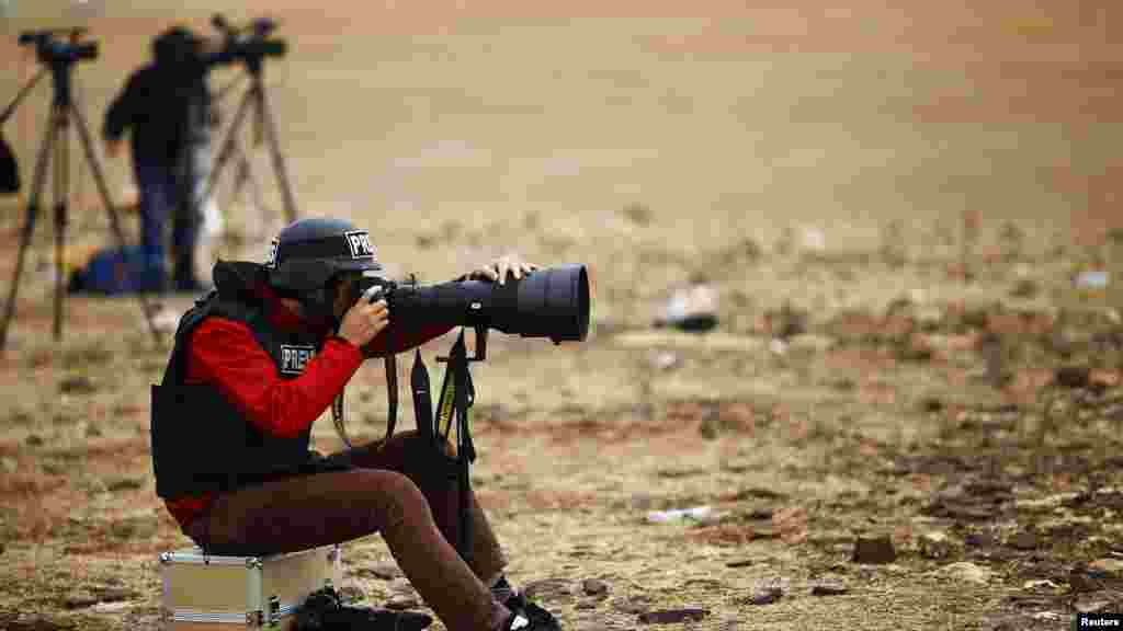 A news photographer takes pictures of the Syrian town of Kobani from near the Mursitpinar border crossing, on the Turkish-Syrian border in the southeastern town of Suruc, Oct. 19, 2014.