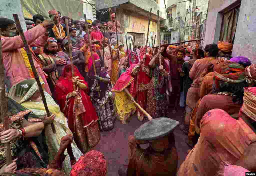 Para wanita Hindu bercadar bermain-main memukuli pria dengan tongkat bambu saat mereka ikut serta dalam perayaan "Lathmar Holi" di kota Nandgaon, Uttar Pradesh, India. (Reuters) 