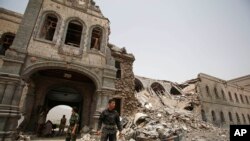 FILE - Shi'ite rebels, known as Houthis, stand guard in front of Yemen's Defense Ministry building in Sanaa, Yemen on June 10, 2015, after it was damaged by Saudi-led airstrikes. 