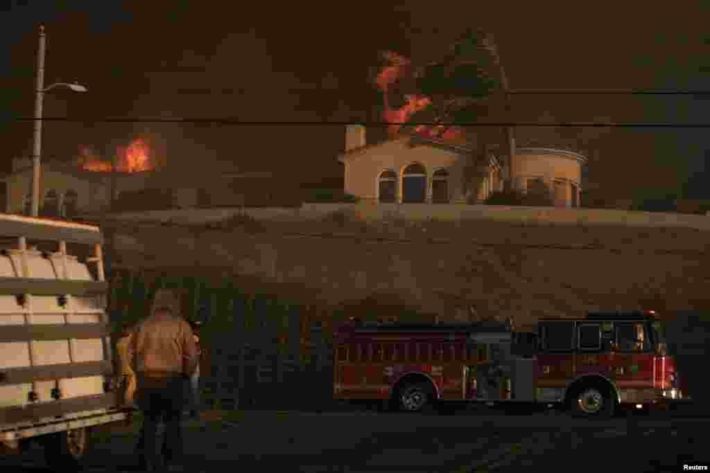 A fire truck heads to another call as a house burns during a wind driven wildfire in Ventura, Dec. 5, 2017.