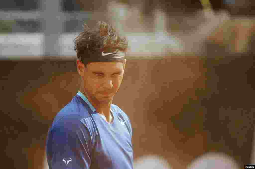 Rafael Nadal of Spain reacts as he takes shelter from sand blown by the wind during the men's singles match against Mikhail Youzhny of Russia at the Rome Masters tennis tournament, Italy.