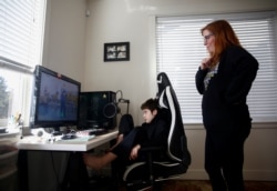 Tracey Pucci dan putranya, Foxton Harding, 12, menonton video yang dibuat oleh para guru Foxton di Northshore Middle School ketika sekolah beralih ke pembelajaran online selama pandemi di Bothell, Washington, AS.