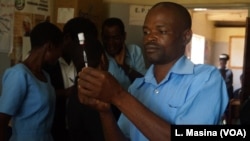 A medical worker at Likuni Community Hospital, in Lilongwe, Malawai, draws the malaria vaccine into a syringe for vaccination.
