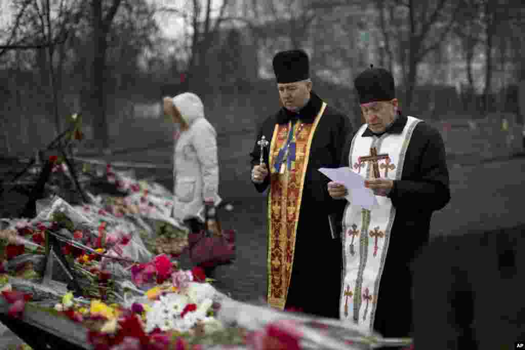 Two priests pray at a memorial for the people killed in clashes with the police at Kyiv's Independence Square, Feb. 28, 2014.