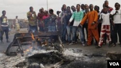 Pendukung presiden Alassane Ouattara menunjuk mayat yang terbakar yang diyakini sebagai pendukung Laurent Gbagbo, di Distrik Abobo, Abidjan (7/3).