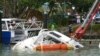 Orang-orang melihat kapal yang rusak di marina di Tutukaka, Selandia Baru, 16 Januari 2022, setelah gelombang dari letusan gunung berapi menyapu marina. (Foto: AP)
