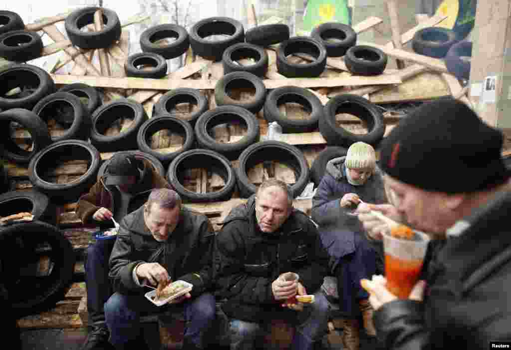Pro-European integration protesters eat free meals near a barricade during a rally in Independence Square in Kyiv, Dec. 16, 2013.