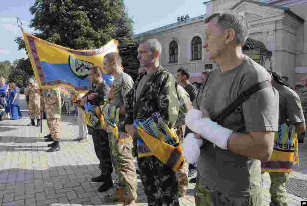 Volunteers of battalion 'Donbas' hold battalion flags during a blessing ceremony in St. Michael Cathedral in Kyiv, Aug. 19, 2014. 