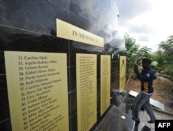Workers mount a plaque as they work on the memorial for the victims of last year's terrorist attack that killed 148 people at the campus of Garissa University College, on April 2, 2016 in Garissa.