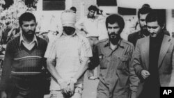 یکی از گروگان‌های سفارت آمریکا در تهران با چشم‌های بسته، به همراه چند تن از انقلابیون طرفدار خمینی - ۹ نوامبر ۱۹۷۹ 