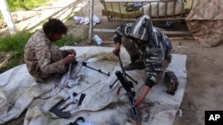FILE - In this file photo released on June 16, 2015, by Ismamic State militant group supporters on an anonymous photo sharing website, Islamic State militants clean their weapons in Deir al-Zour city, Syria.