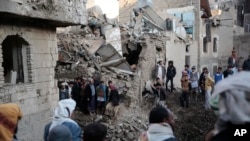 FILE - People gather at the site of a Saudi-led airstrike near Yemen's Defense Ministry complex in Sanaa, Yemen, Saturday, Nov. 11, 2017. 