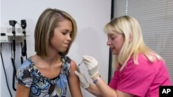 FILE - Lauren Fant, left, winces as she has the human papillomavirus (HPV) vaccine administered by nurse Stephanie Pearson at a doctor's office in Marietta, Ga., Dec. 18, 2007. 