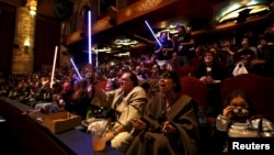 FILE - Moviegoers cheer and wave lightsabers before the first showing of the movie "Star Wars: The Force Awakens" at the TCL Chinese Theatre in Hollywood, California, Dec. 17, 2015.