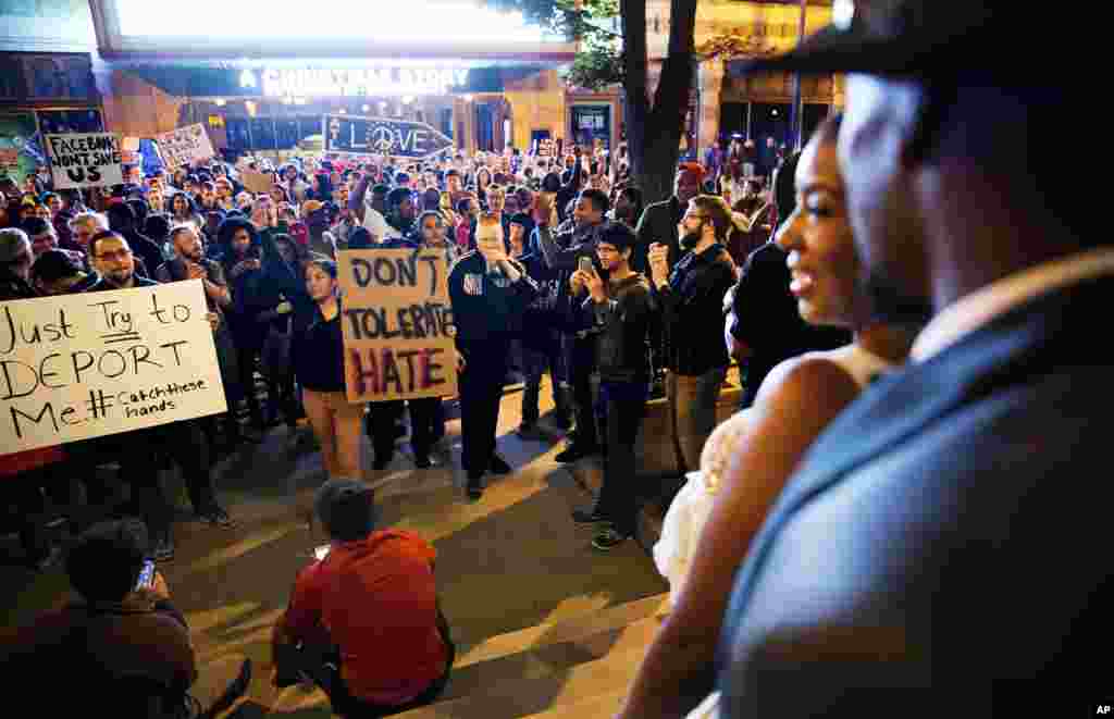 Siedric, right, and Sadio White, step out of a hotel during their wedding party to look on as a protest pauses in the street during a march against the election of President-elect Donald Trump in Atlanta, Friday, Nov. 11, 2016. 