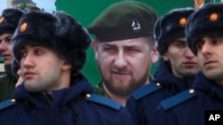 FILE - Newly-drafted Chechen conscripts, who were called to service in autumn, stand in front of a portrait of Chechen regional leader Ramzan Kadyrov as they prepare to march in Grozny, Russia, Nov. 28, 2017.
