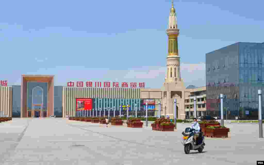 A woman drives her motorbike through the almost empty square in front of the Yinchuan International Trade Mall, which is aimed at spurring development of the region's commerce in mostly Islam-related products. (Stephanie Ho/VOA)