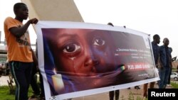 FILE - People carry a banner during a remembrance ceremony for the children who were killed during an attack on the Dogon village of Sobane Da, at the Monument de la Paix in Bamako, Mali, June 15, 2019.