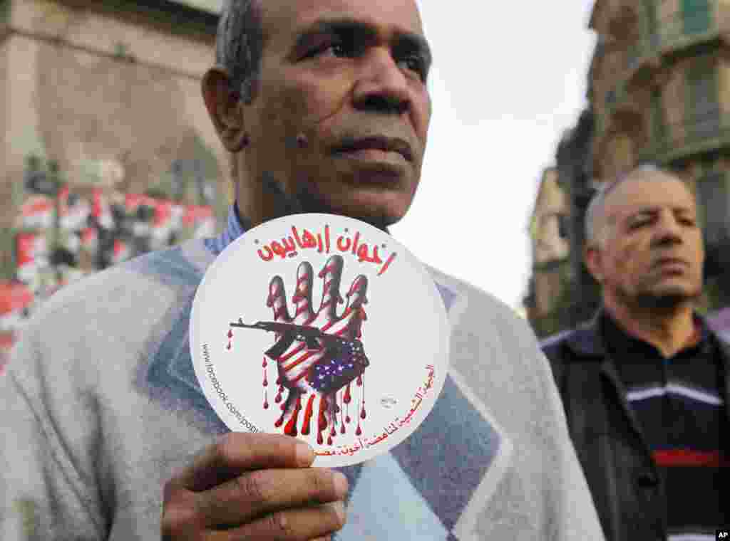 An activist holds a sign with an anti-terrorism picture and Arabic that reads "terrorists brotherhood" during an anti-terrorism demonstration in Cairo, Dec. 26, 2013.