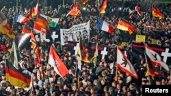 FILE - Supporters of anti-immigration movement Patriotic Europeans Against the Islamization of the West (PEGIDA) hold flags during demonstration in Dresden, Germany, Jan. 12, 2015.