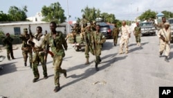 Somali soldiers patrol near the wreckage of a car bomb that was detonated at the main gate of the presidential palace in Mogadishu, Somalia, July, 9, 2014. 