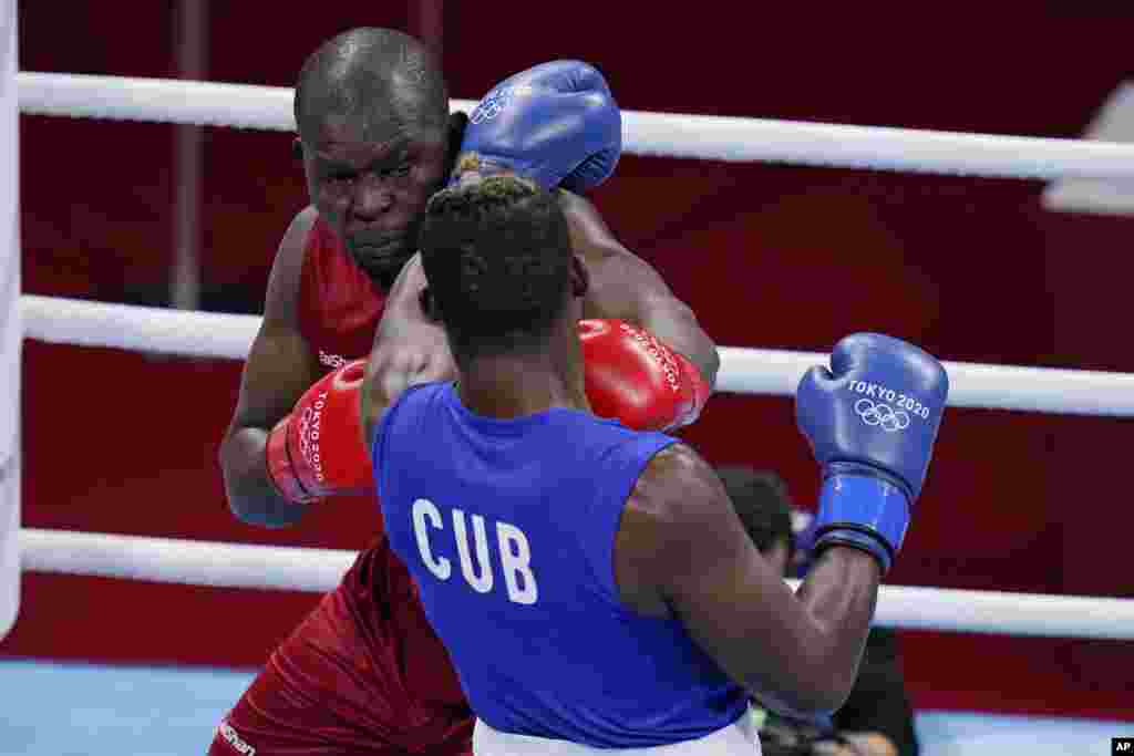 Kenya's Elly Ajowi Ochola, left, exchanges punches with Cuba's Julio la Cruz during their men's heavyweight 91-kg boxing match at the 2020 Summer Olympics, Tuesday, July 27, 2021, in Tokyo, Japan. (AP Photo/Frank Franklin II)